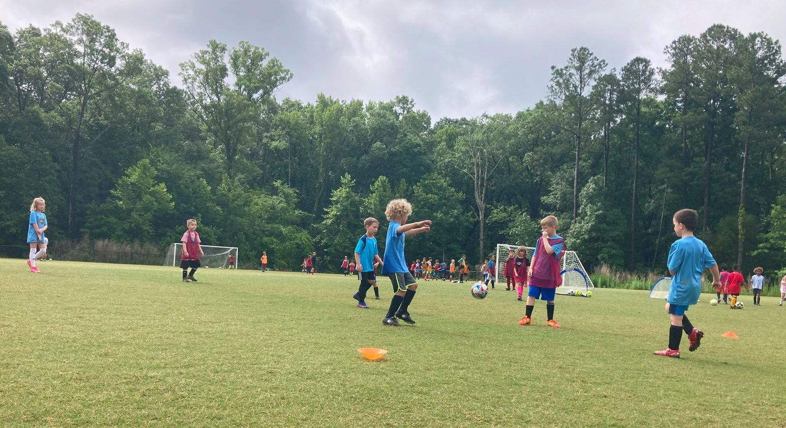 Young recreation players training on a grass field with cone markers